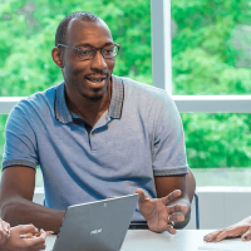 Two women and a man sit around a table in discussion at work.