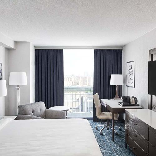 Hotel room with bed, tv, arm chair, desk, and window