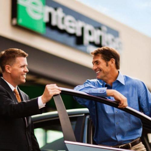 Man smiling as an Enterprise car rental employee shows him his rental car