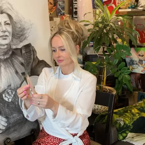 Erin Finley sits in her art studio surrounded by paintings.