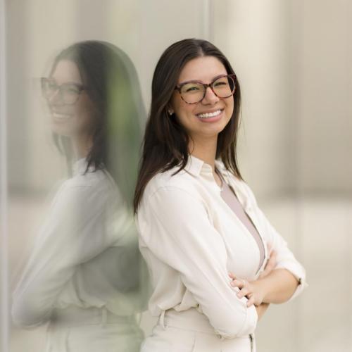 Thaisa stands with her arms crossed, smiling
