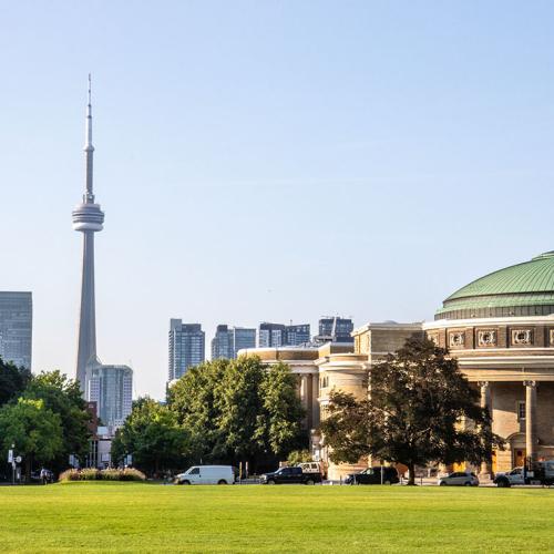 The lawn of Front Campus stretches out towards Convocation Hall, with the CN Tower in the background.
