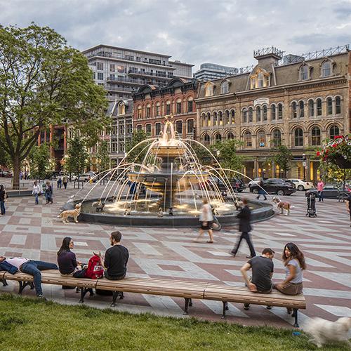 People play and relax around the huge fountain in Berczy Park. The three-tier structure features 27 cast-iron dogs.