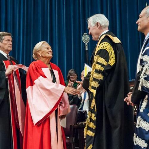 Loretta Rogers, who today received an honorary doctor of laws, honoris causa, shakes the hand of Chancellor Michael Wilson, as President Meric Gertler (right) and Toronto Mayor John Tory look on (photo by Lisa Sakulensky)