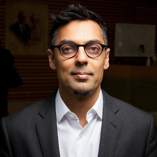 Portrait of Kamran Khan smiling slightly in an indoor lobby.