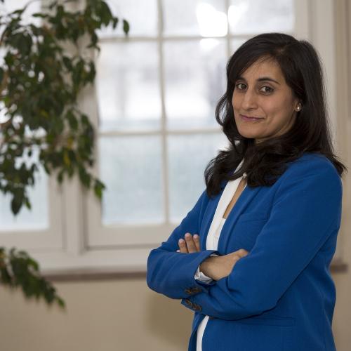 Anita Anand smiles as she stands indoors by a window.