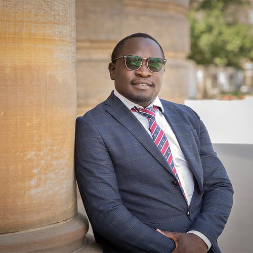 Michael Samakayi  smiles as he leans on a pillar outside Convocation Hall.