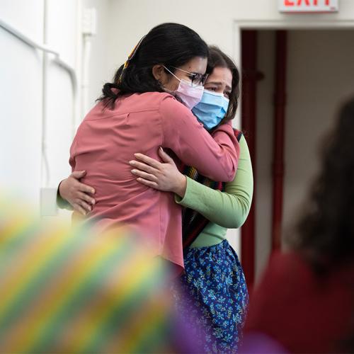 Kristine Keon and Angelique Belcourt, wearing masks, hug tearfully at the Indigenous Grad celebration.