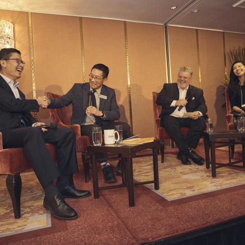 Four people sit on stage talking and laughing.