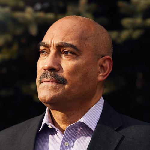 Akwatu Khenti looks serious as he stands outside at sunset.