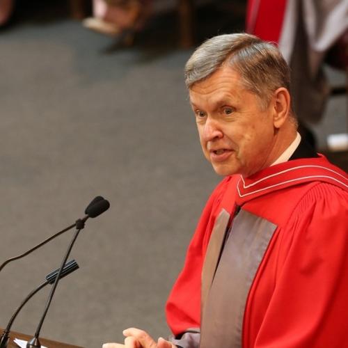Alfred Aho talks while wearing academic robes and standing at a podium.