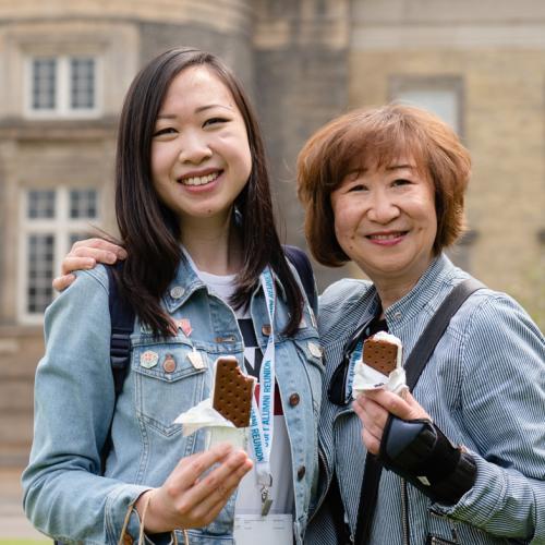 Two alumni posing together with ice cream in their hands.