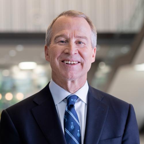 Brian Lawson smiles as he stands in the atrium of a lofty building.