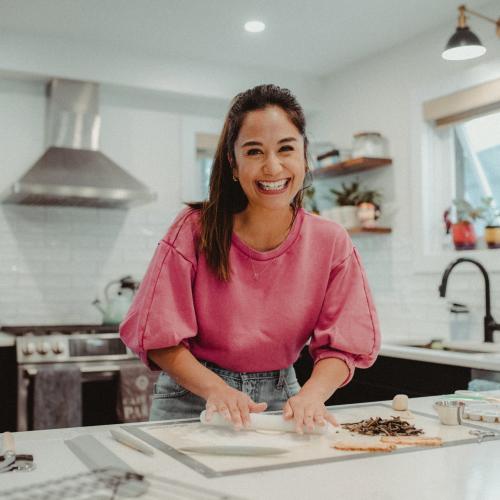 April Julian laughs as she rolls out pastry in a sunny home kitchen.