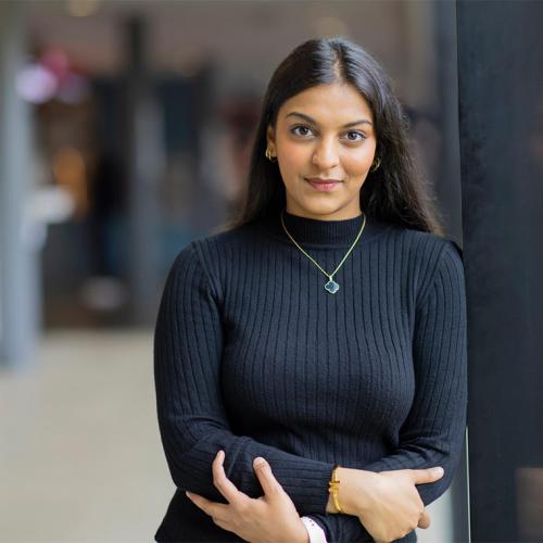Vanshika Agarwal leans on a wall with arms crossed.
