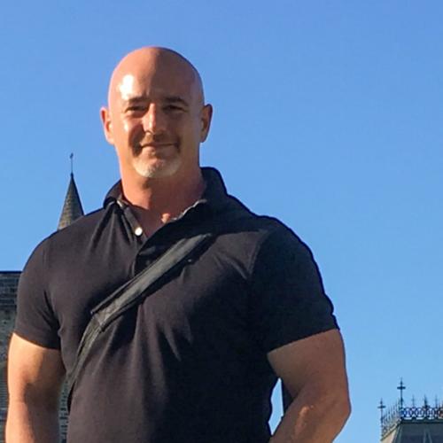 John Montefiore smiles, standing against a sunny sky on Front Campus.