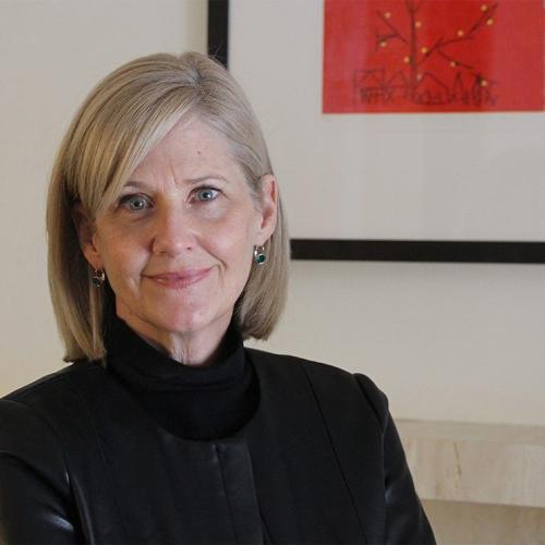 Barbara Fallon smiling in front of an abstract artwork.