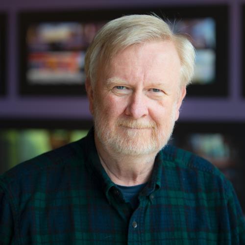 A portrait of Bill Reeves wearing a plaid shirt