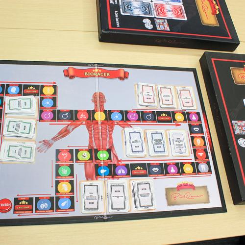 The BioRacer board game laid out on a table. Piles of cards match symbols pictured along a winding path on the game board.