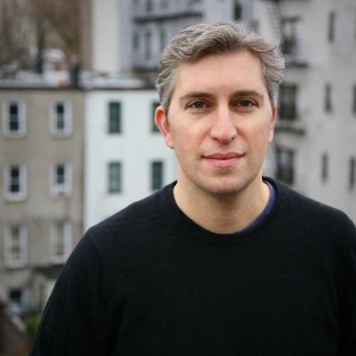 Andrew Blum standing outside with houses in the distance