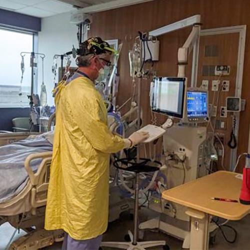 Marco Caminiti, wearing full protective equipment, accesses a console in an intensive care room.