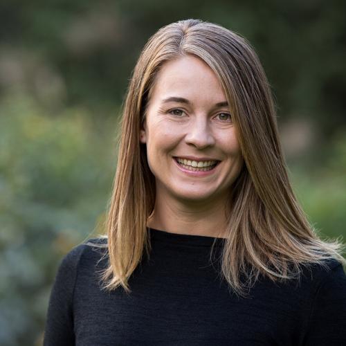 A portrait of Maaike Canrinus smiling in front of some greenery