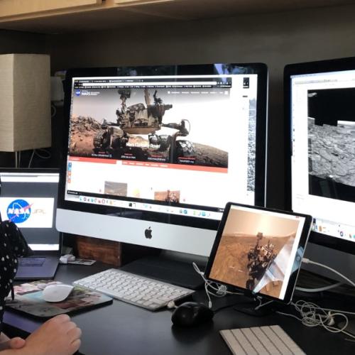 Carrie Bridge in her home office with multiple screens and keyboards surrounding her