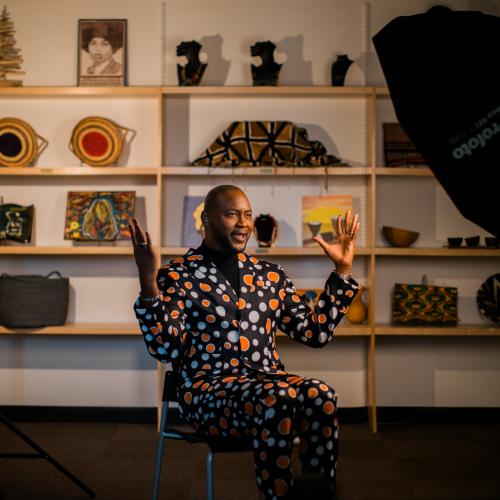 A Black man sitting in a chair and talking expressively