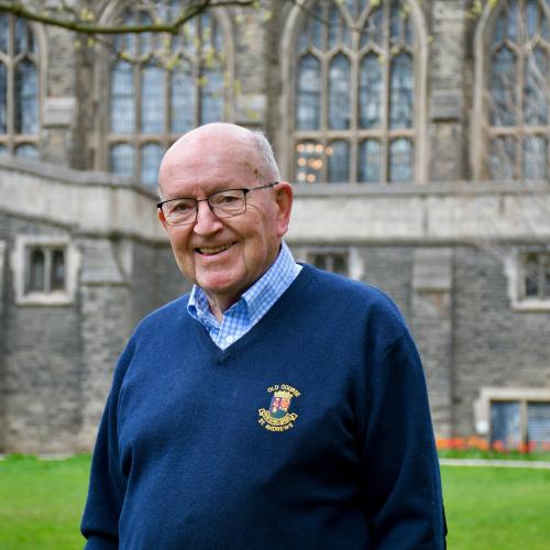 Bob Burrows in a blue sweater standing in front of Burwash Hall