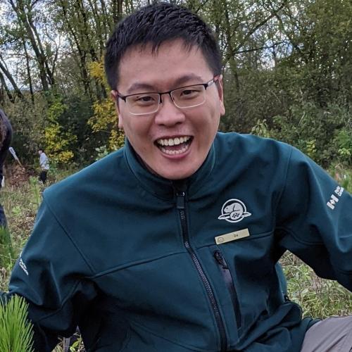 Da Chen smiles as he holds a tree seedling ready to plant.