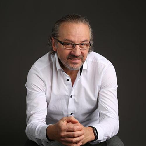 Andras Nagy sits leaning forward and looks up, smiling.