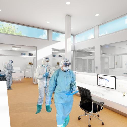 Workers in protective clothing walk down an open hallway lit by overhead windows.