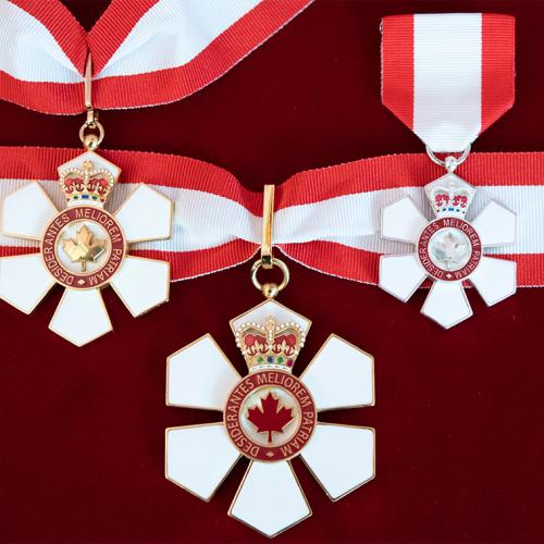 Three Order of Canada medals. The six-petalled medal has a maple leaf in the centre and hangs on a ribbon.