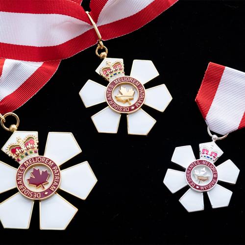 The Order of Canada medal is shaped like a six-petalled flower with a maple leaf centre, hanging from a red and white ribbon.