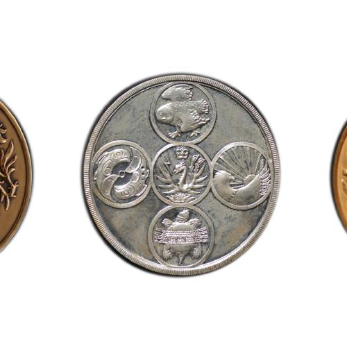 An image of the Governor General's medals. The gold shows a shield held up by mermaids and the motto: Briser les solitudes.