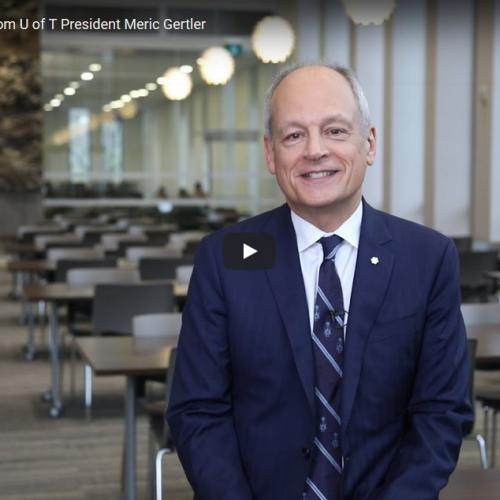 Meric Gertler smiles as he stands in a library reading room in a scene from his holiday video.