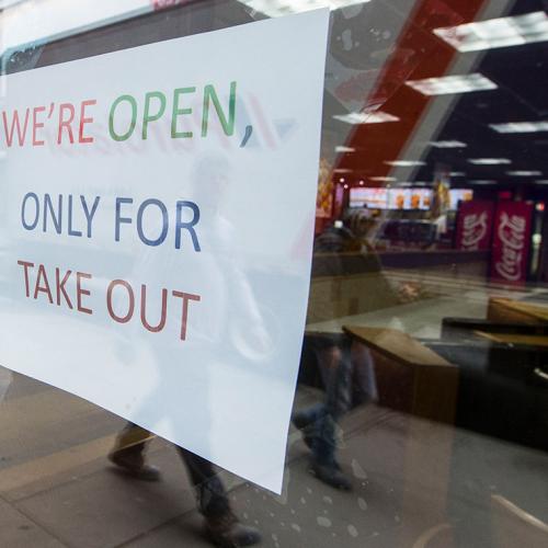 A sign in a restaurant window reads: We're open, only for takeout.