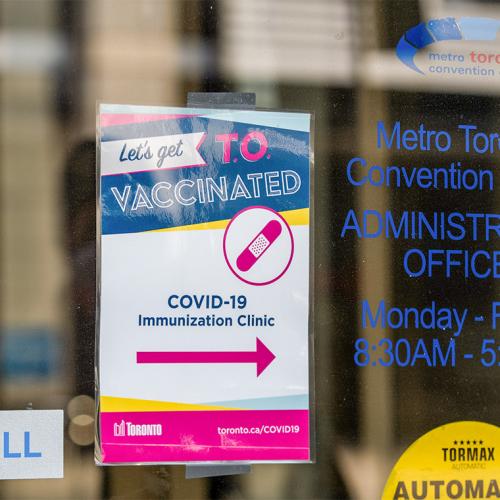 A sign for a COVID-19 vaccination clinic posted on the door of the Metro Toronto Convention Centre offices.