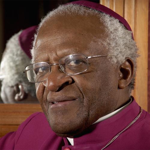 Archbishop Desmond Tutu smiles quietly. He wears a formal skullcap and gown.