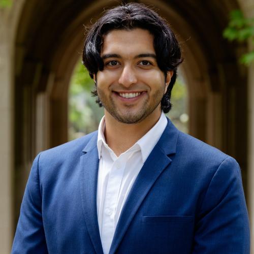 A portrait of a young person smiling and wearing a blue business suit. 