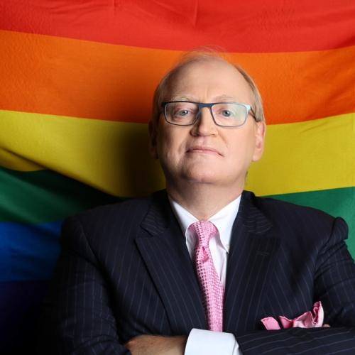 Douglas Elliott standing in front of a Pride flag