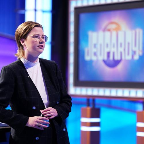 Mattea Roach stands next to a sign that says, Jeopardy!