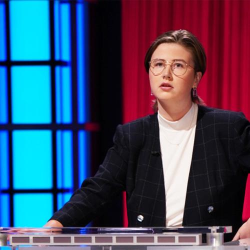Mattea Roach looks thoughtful, standing on the Jeopardy TV set and choosing a category.