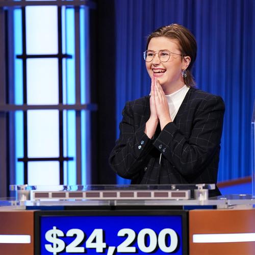 Mattea Roach smiles and claps, standing at a Jeopardy podium. The dollar total on her screen reads $24,200.