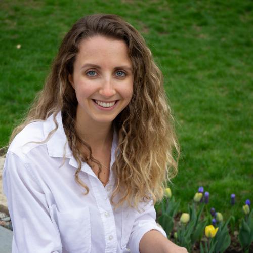 Jillian Sprenger smiles as she sits in a garden with blossoming tulips.