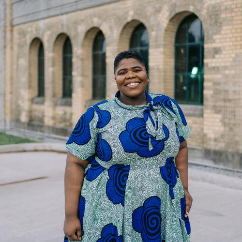Joelleann Forbes stands outside in front of a building, smiling. 