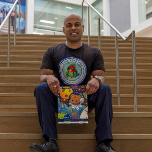 A man seated on a staircase holding a book