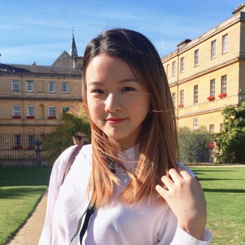 Juliana Lee smiles while standing in a grassy quad between old buildings.