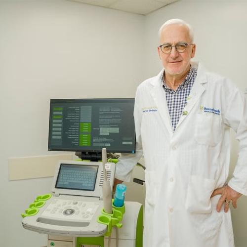 A man in a white lab coat standing next to a piece of medical equipment