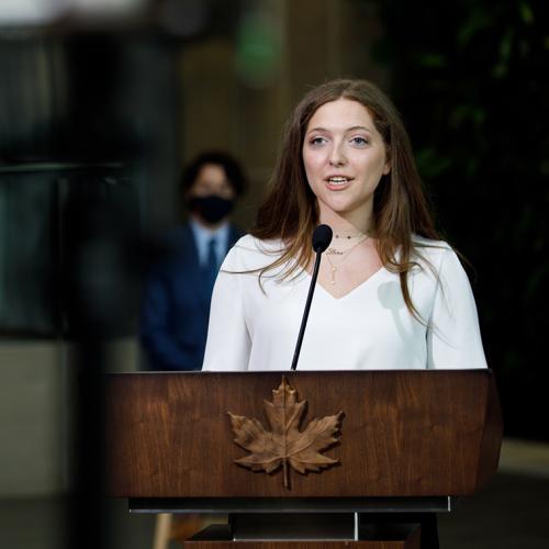 Lana El Sanyoura talks at a podium emblazoned with a carved wooden maple leaf.